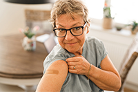 An women showing a band aide from where she received a vaccine