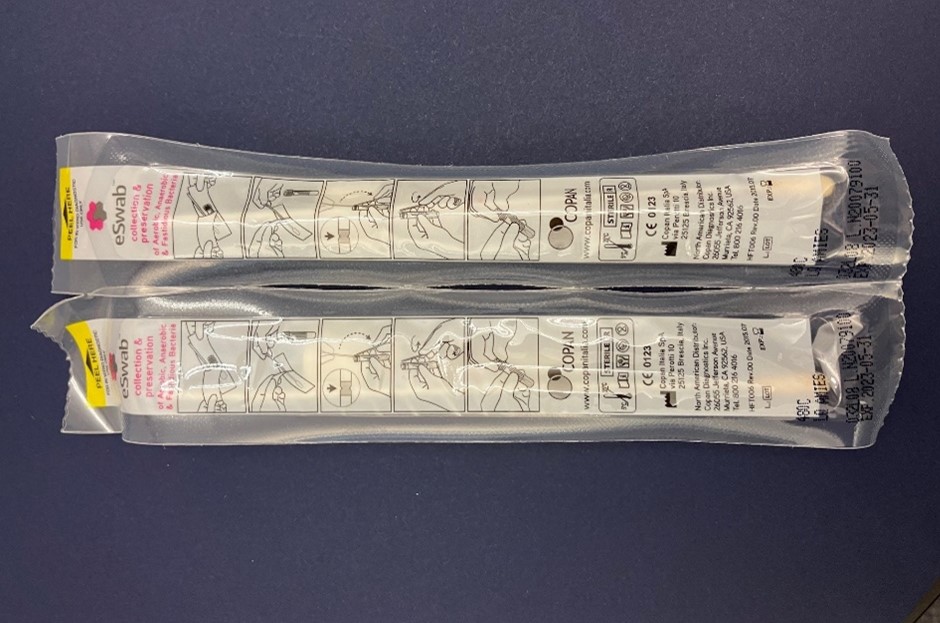 "An overhead image of the top side of two sealed, unopened ESwab Collection Kits for Candida clinical specimen collection. Kit expiration dates are visible at the bottom of the swab packets. "