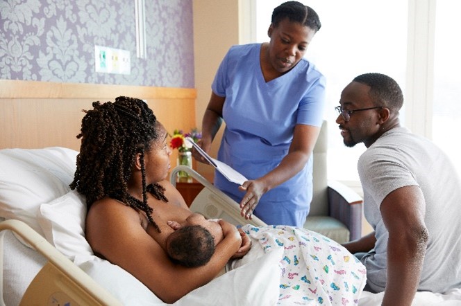 A mother breastfeeding her child with doctor and father in the room. 