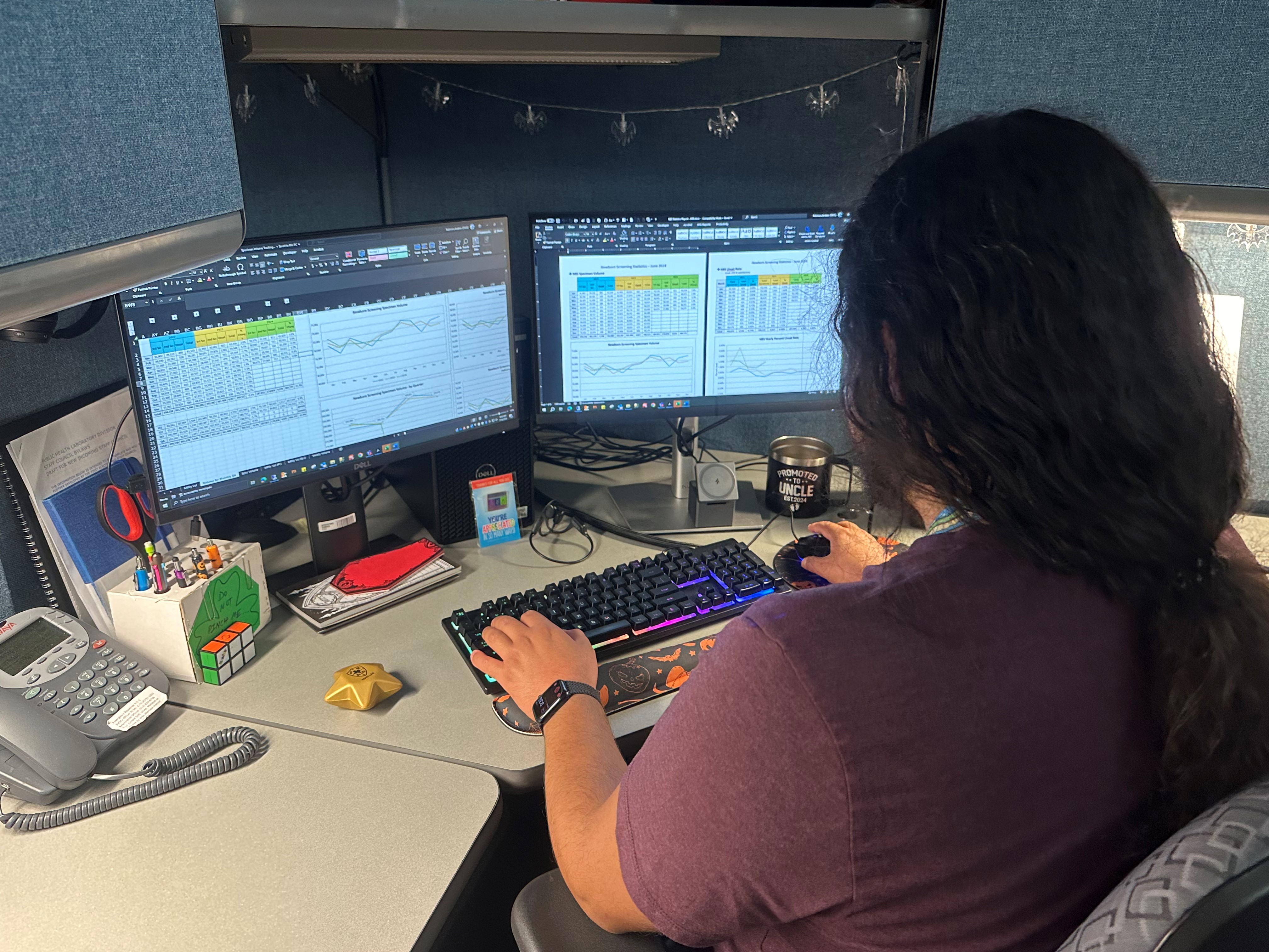 Informatics personnel sitting at computer compiling data.