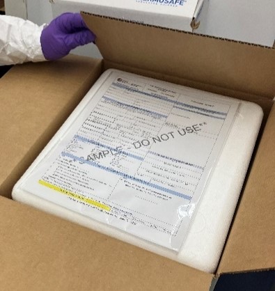 A gloved hand closed the lid of a shipping box containing an insulated polystyrene container