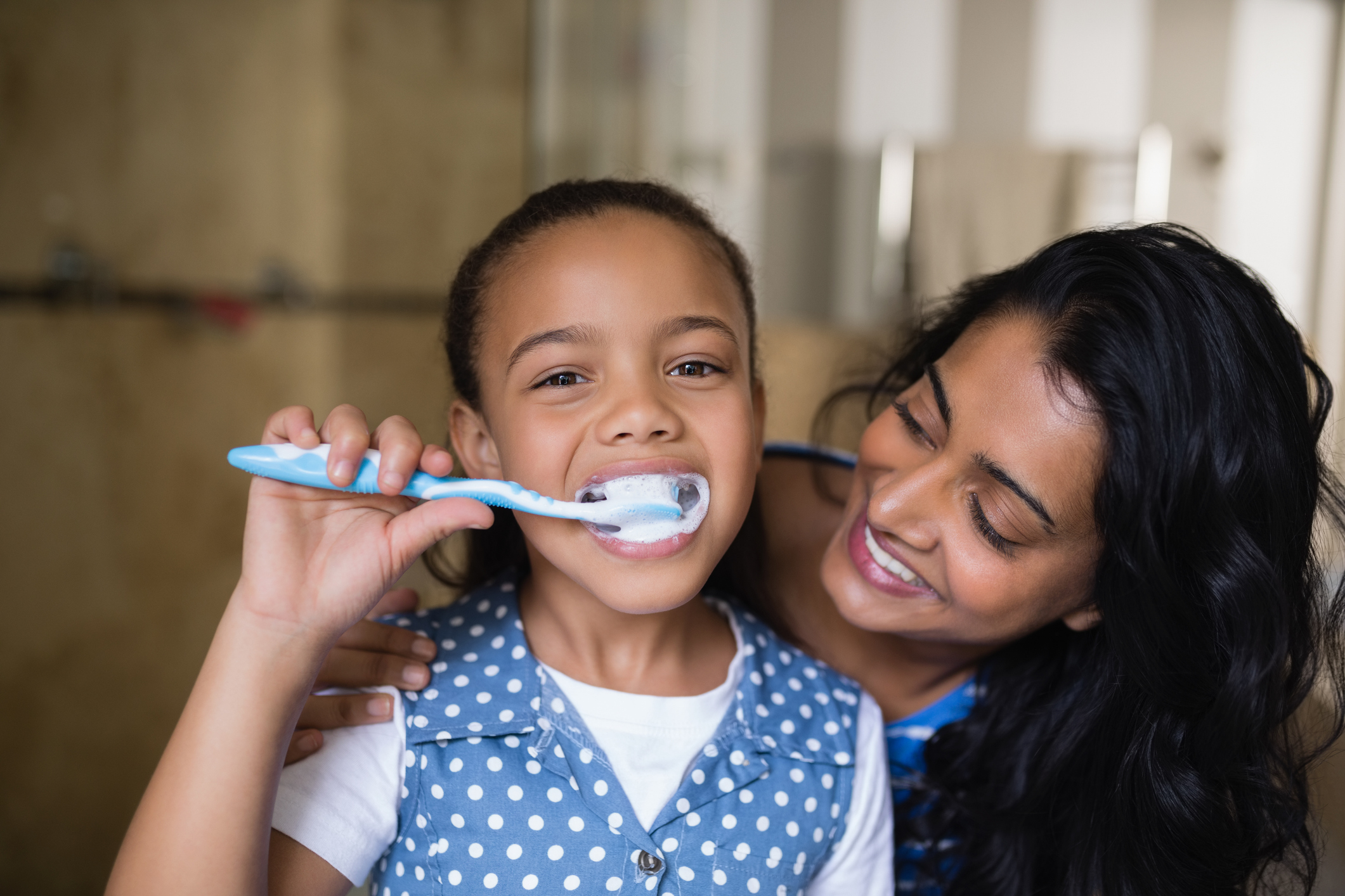 Parent watching child brush their teeth
