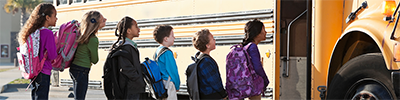 Children lined up to get on a school bus.