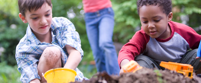 Children play with toy trucks in the dirt